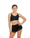 Young woman wearing a black sports bra and shorts on a white background