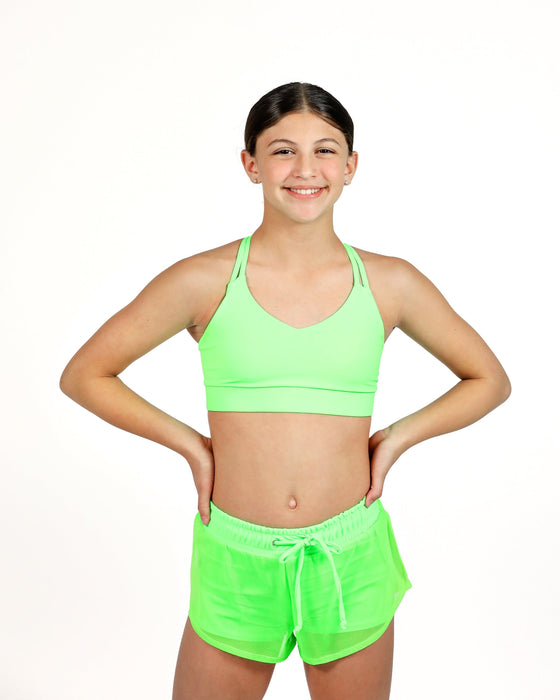 Person wearing a bright green sports bra and shorts set on a white background