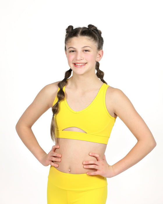 Young girl wearing a yellow sports bra and leggings on a white background