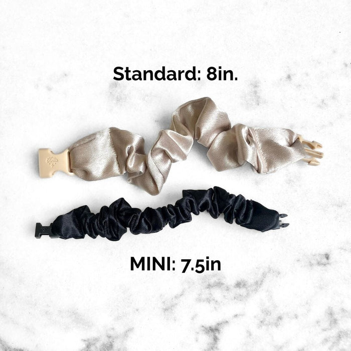 Two satin scrunchies and a black hair tie on a marble surface with size labels.