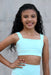 Young girl wearing a light blue athletic outfit against a neutral background