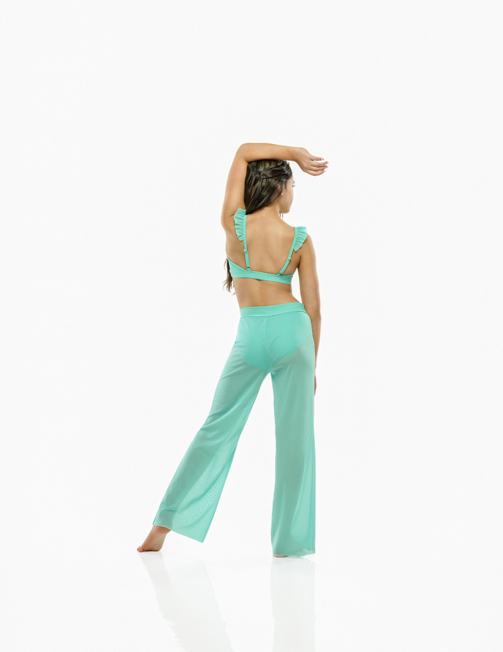 A woman posing from behind wearing a mint green two-piece set consisting of a ruffled halter-style crop top and matching wide-leg pants, set against a plain white studio background.