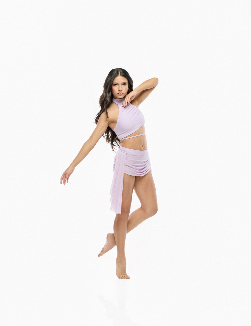 A woman modeling a light lavender belly dancing costume set consisting of a halter crop top and a matching draped wrap skirt, posed against a seamless white background.