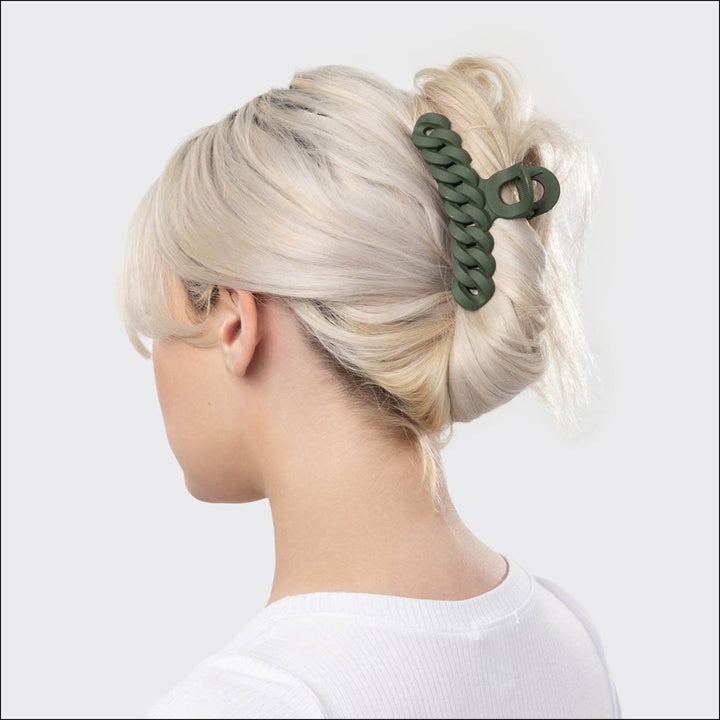 Person with blonde hair tied in a ponytail using a green hair tie against a white background