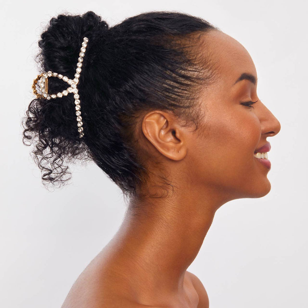 Woman with styled hair featuring a decorative hairpin on a plain background