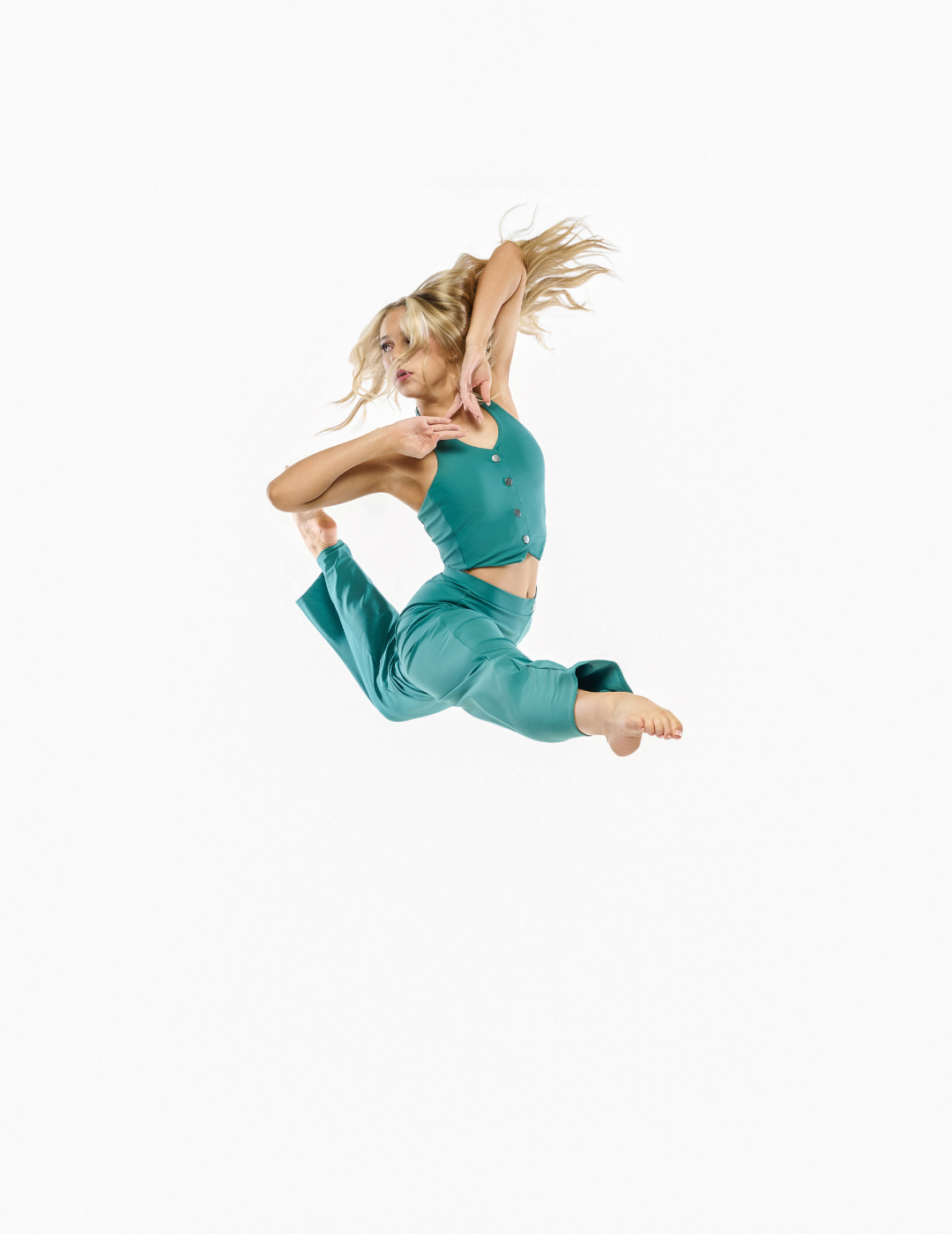 A woman in a teal green activewear set consisting of a cropped tank top and matching pants, captured mid-air in a dynamic split leap against a solid white background.