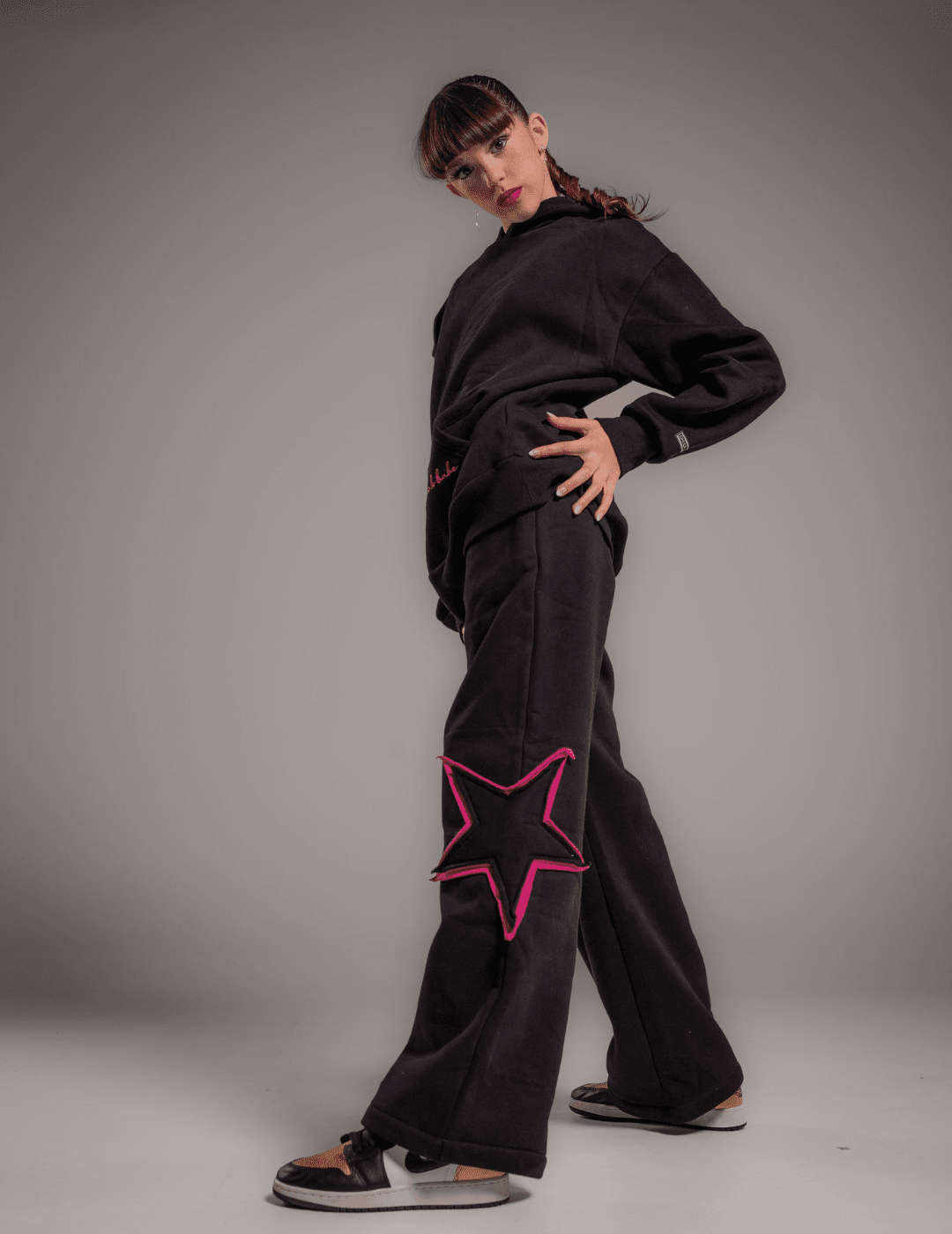 Person wearing a black outfit with pink star designs on a gray background