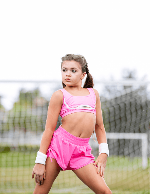 Young girl in pink athletic wear on a tennis court