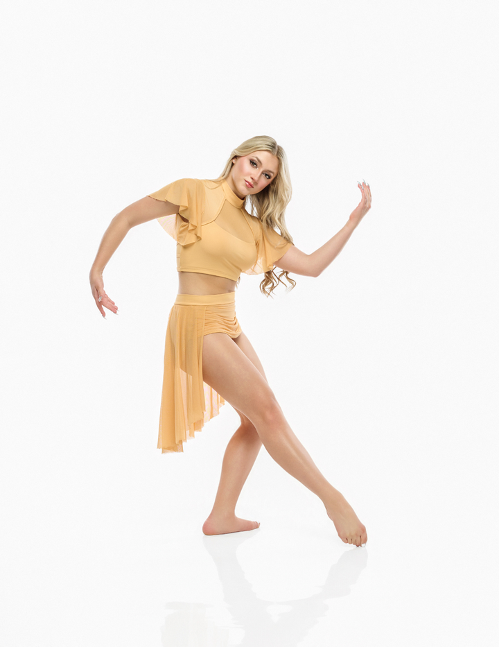 A woman posing in a two-piece dance or yoga outfit in a warm mustard yellow color, featuring a ruffled short-sleeve crop top and a matching high-waisted wrap skirt, set against a seamless white studio background.