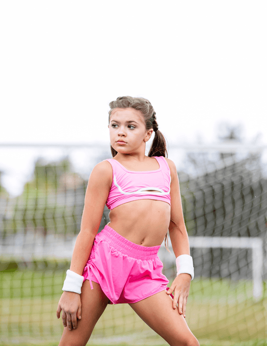 Young girl in pink athletic wear on a tennis court