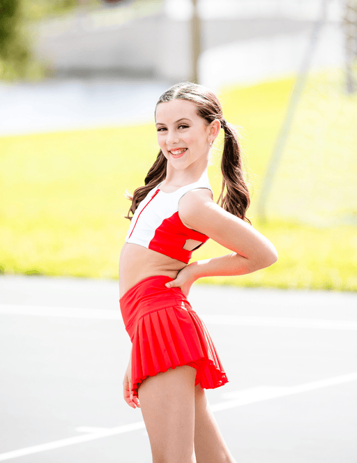 Woman in a red and white sports outfit standing outdoors with a blurred background