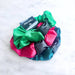 Colorful satin hair scrunchies with black buckles on a marble surface
