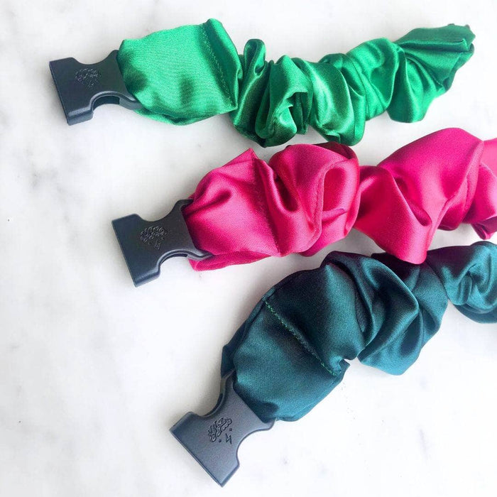 Three satin scrunchies in green, pink, and blue on a white background