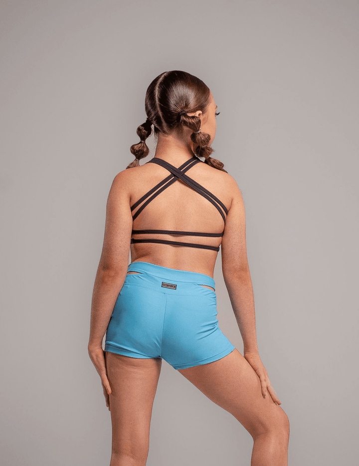 Person wearing a black strappy top and blue shorts on a gray background