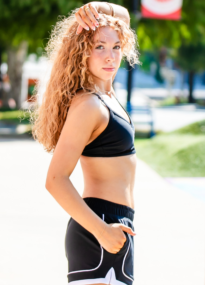 Woman in athletic wear standing outdoors with trees and a blurred background