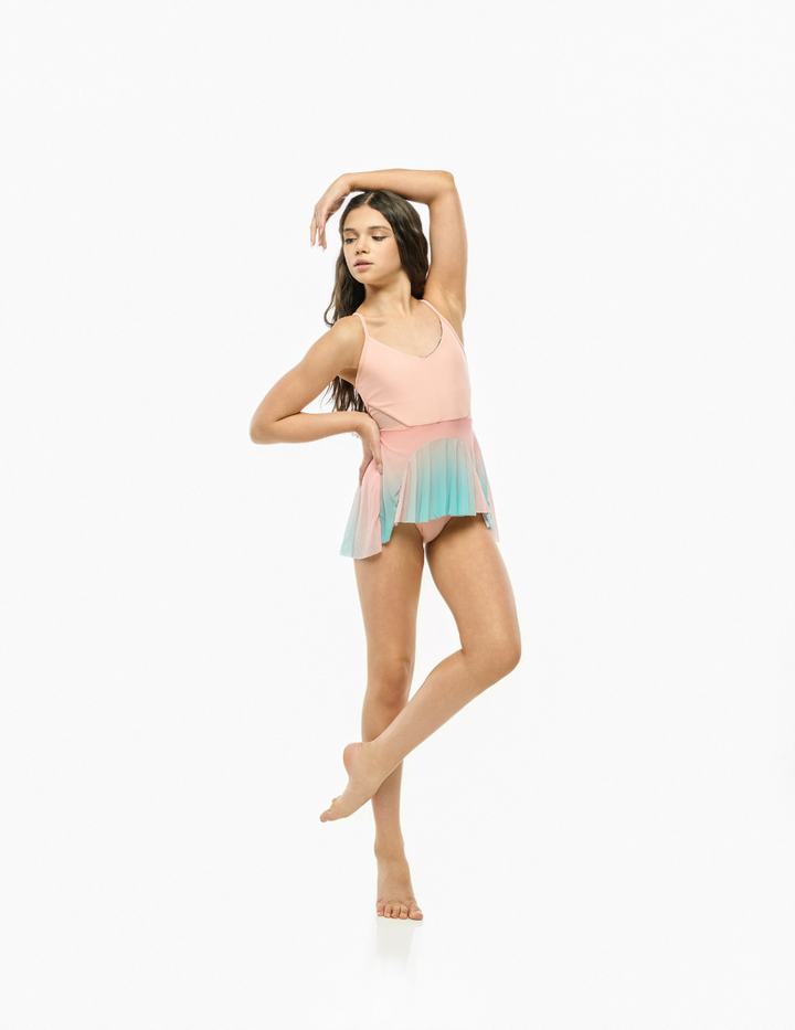 A young dancer posing in a sleeveless pastel leotard with a pink-to-blue gradient skirt, set against a plain white studio background.