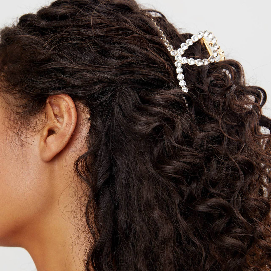 Close-up of a person with curly hair wearing a decorative hair clip.
