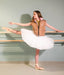 Ballerina in a white tutu and brown vest practicing at a barre against a plain wall.
