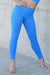 Person wearing bright blue leggings standing against a concrete wall.