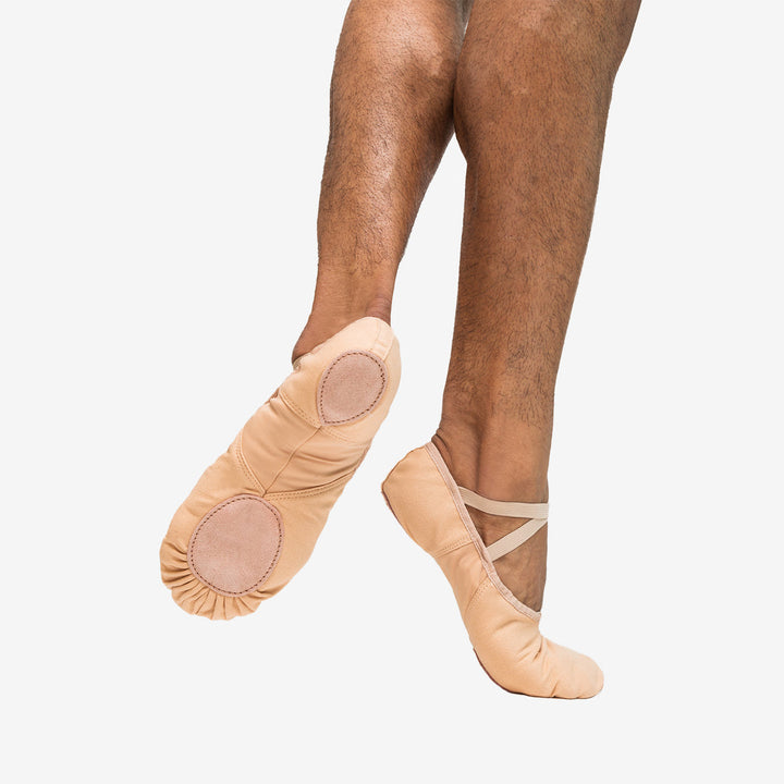 Ballet shoes worn on feet against a plain background