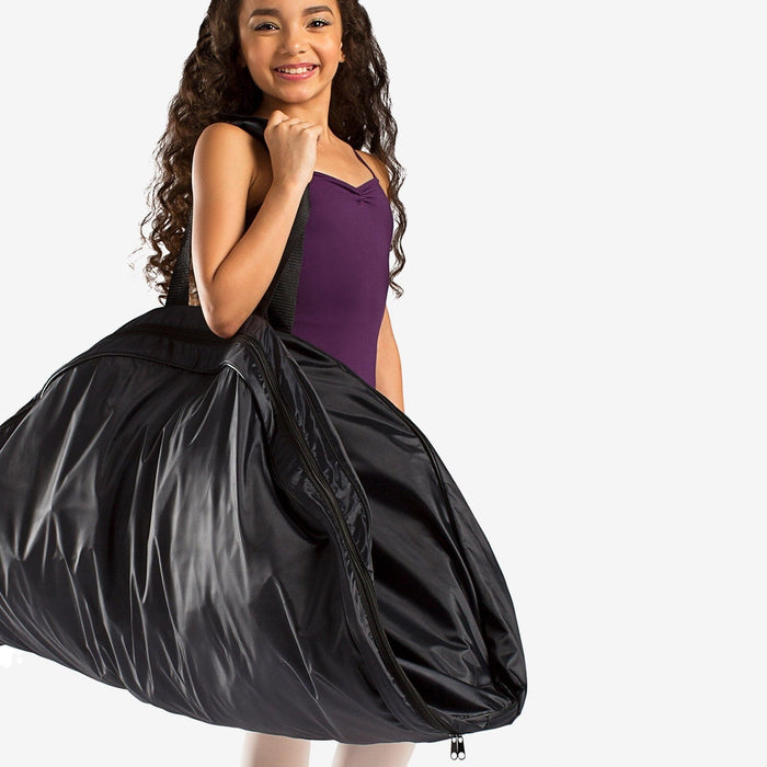 Young girl holding a black dance costume bag on a white background