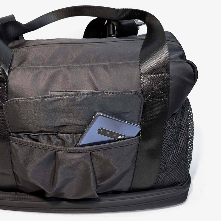 Black backpack with a pocket holding a blue phone on a white background