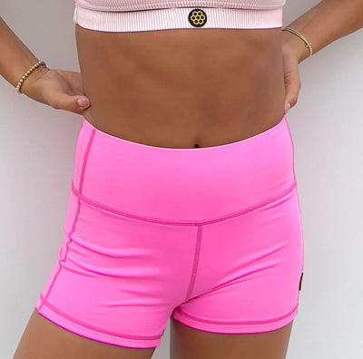 Person wearing bright pink athletic shorts on a plain background
