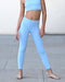 Person wearing light blue athletic leggings and sports bra on a neutral background
