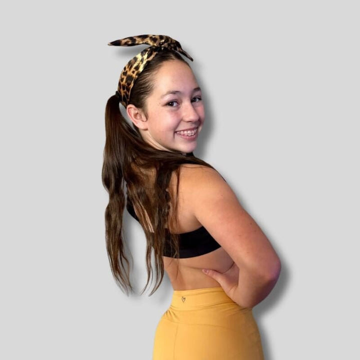 Person wearing a leopard print headband with a plain background