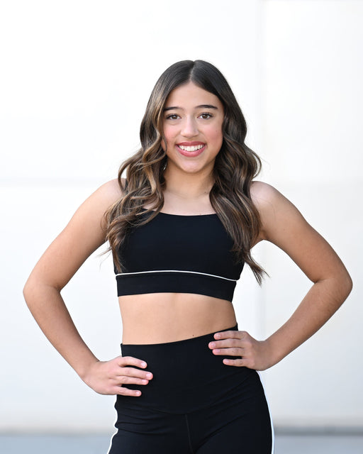Woman wearing a black sports bra and leggings on a white background