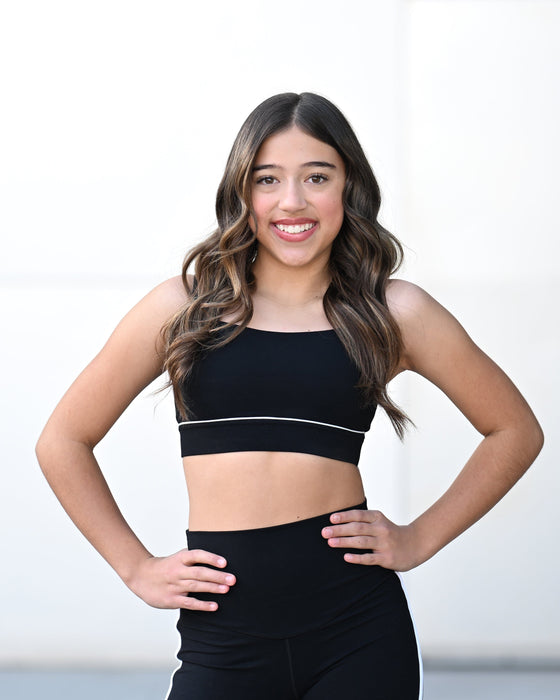 Woman wearing a black sports bra and leggings on a white background