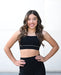 Woman wearing a black sports bra and leggings on a white background