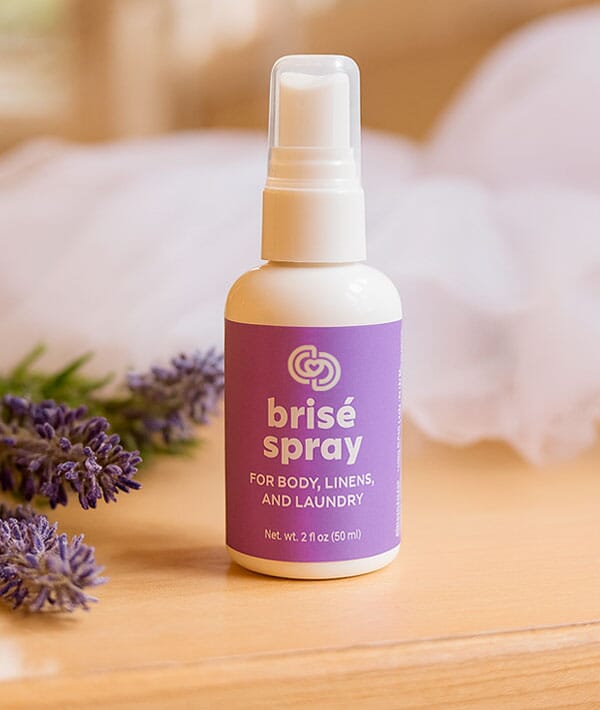 Brisé spray bottle with lavender flowers on a wooden surface