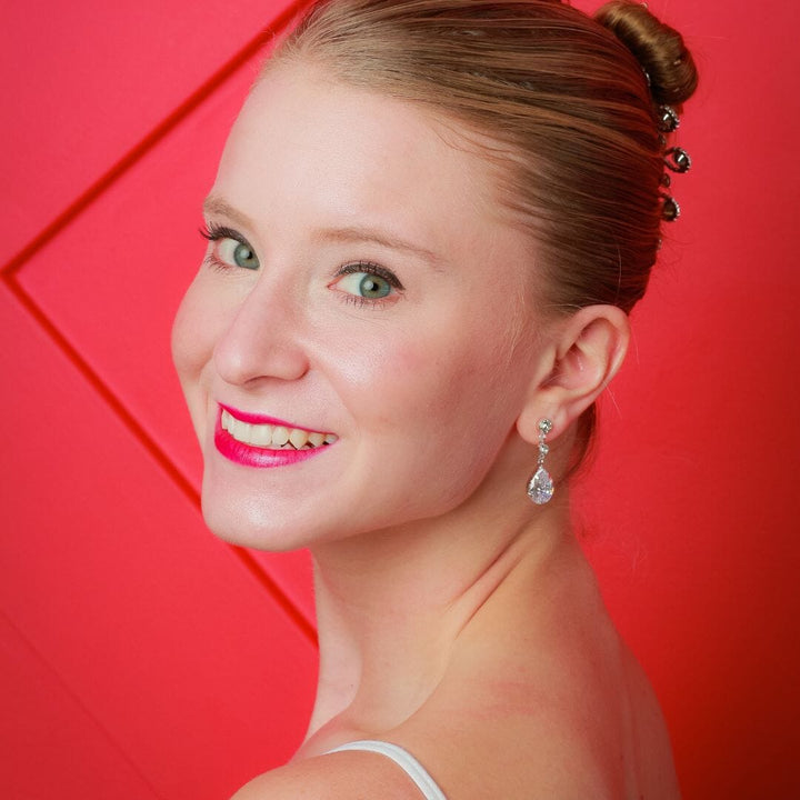 Woman with styled hair and earrings against a red background