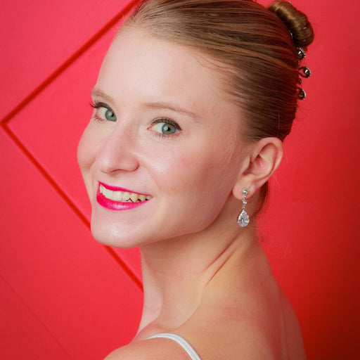 Woman with styled hair and earrings against a red background