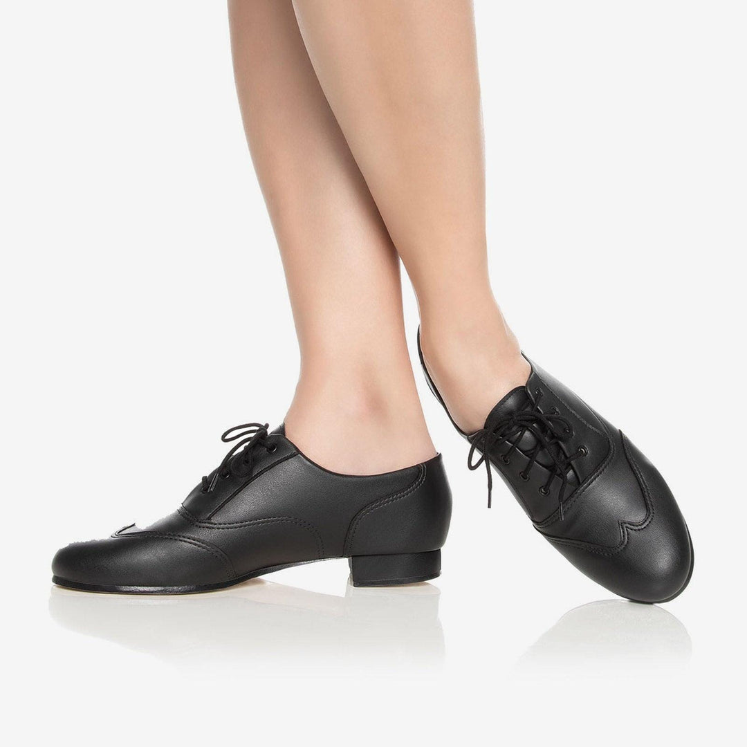 Black dance shoes worn by a person on a white background