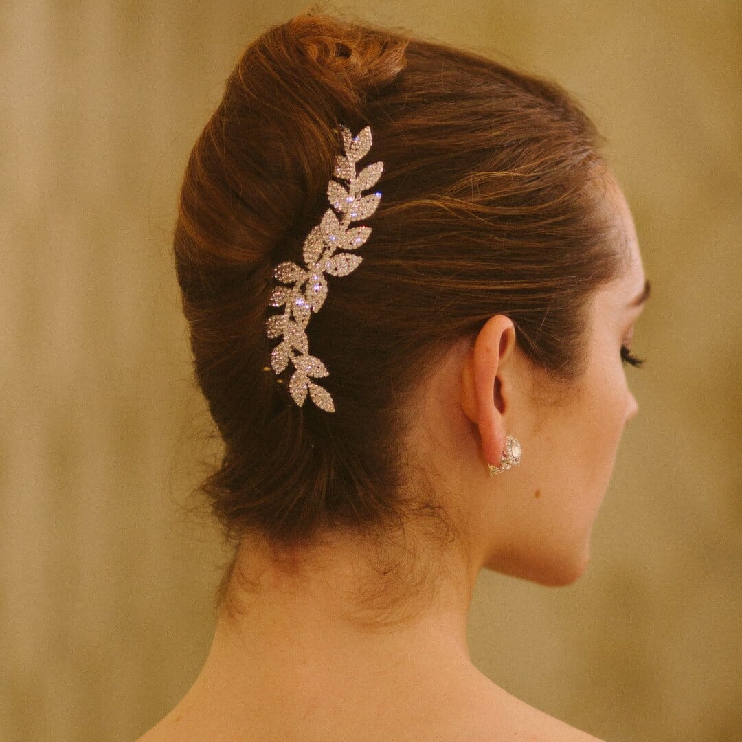 Woman with a decorative hairpiece and earrings against a beige background