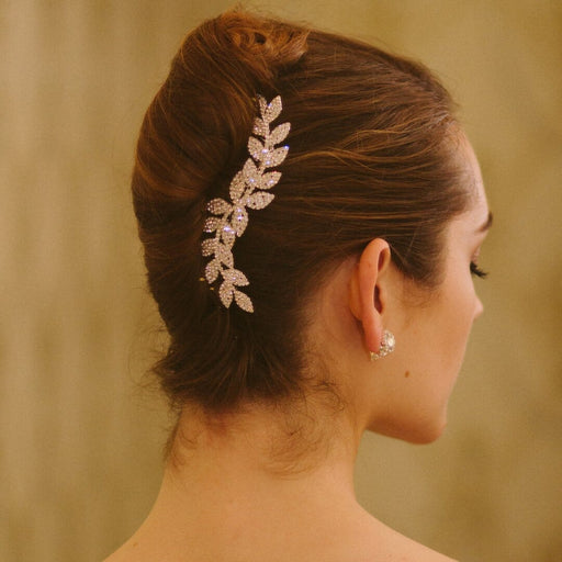 Woman with a decorative hairpiece and earrings against a beige background