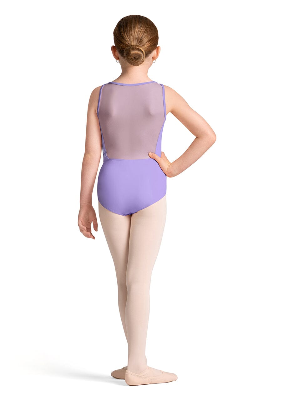 Young girl in a purple leotard and beige tights standing against a white background