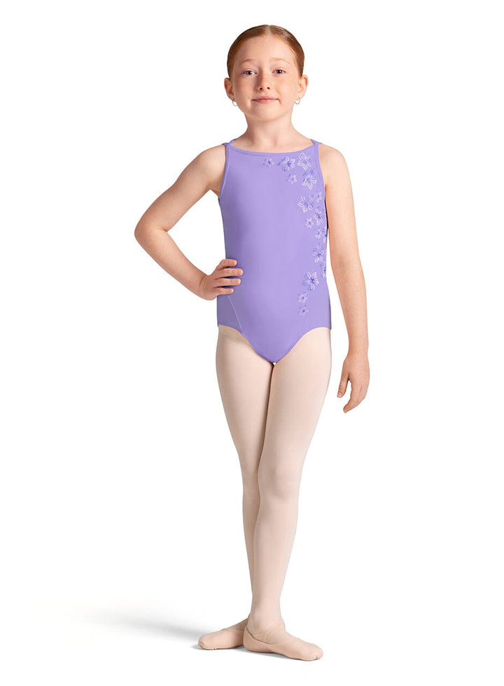 Young girl wearing a purple leotard with floral patterns on a white background