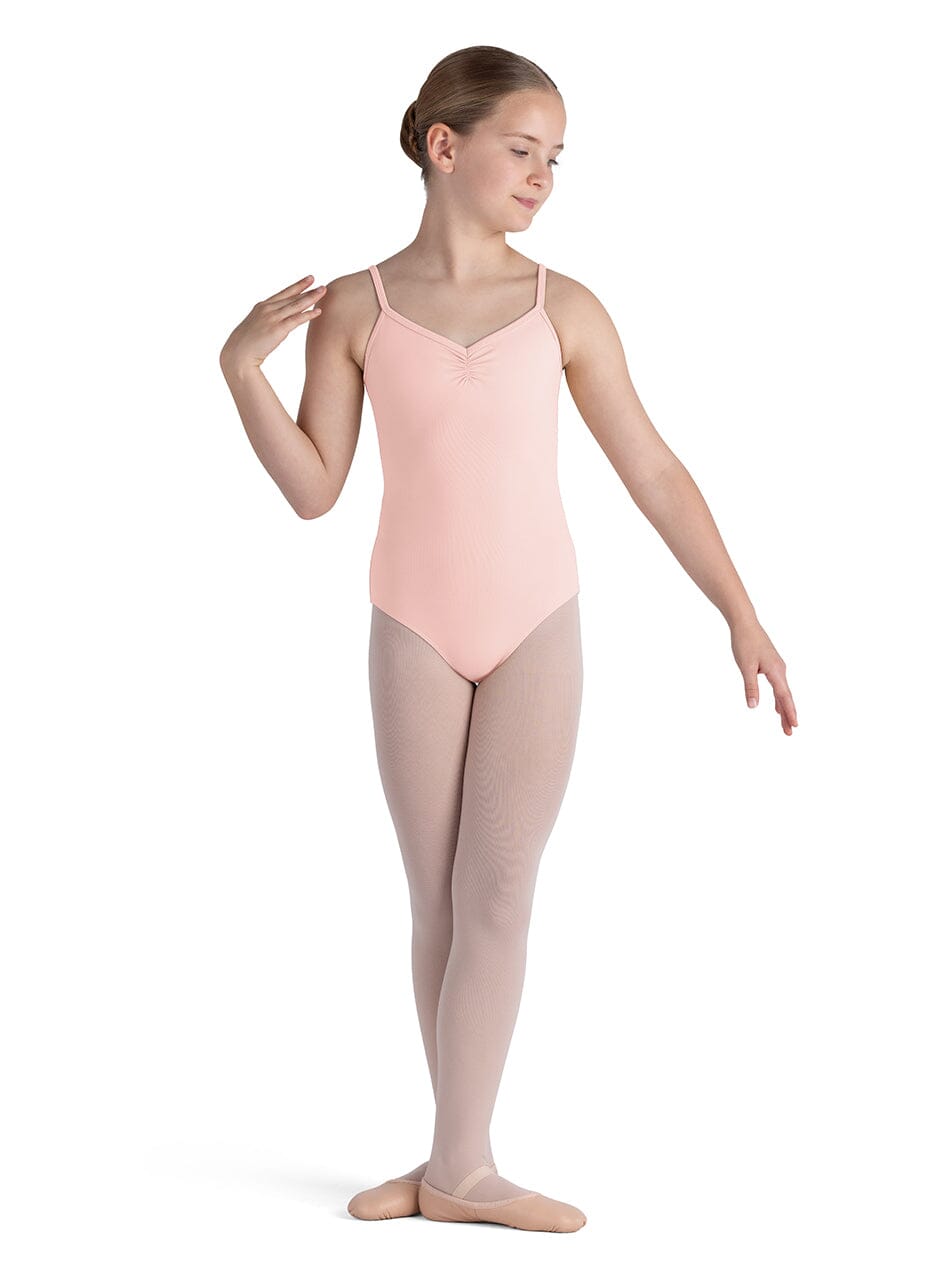 Young dancer in a pink leotard and beige tights on a white background