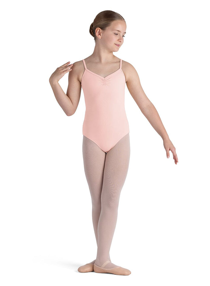 Young dancer in a pink leotard and beige tights on a white background