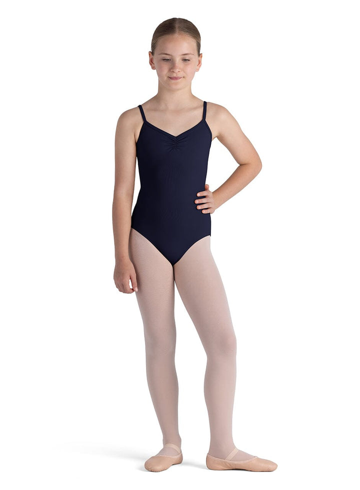 Young girl in a navy leotard and beige tights on a white background