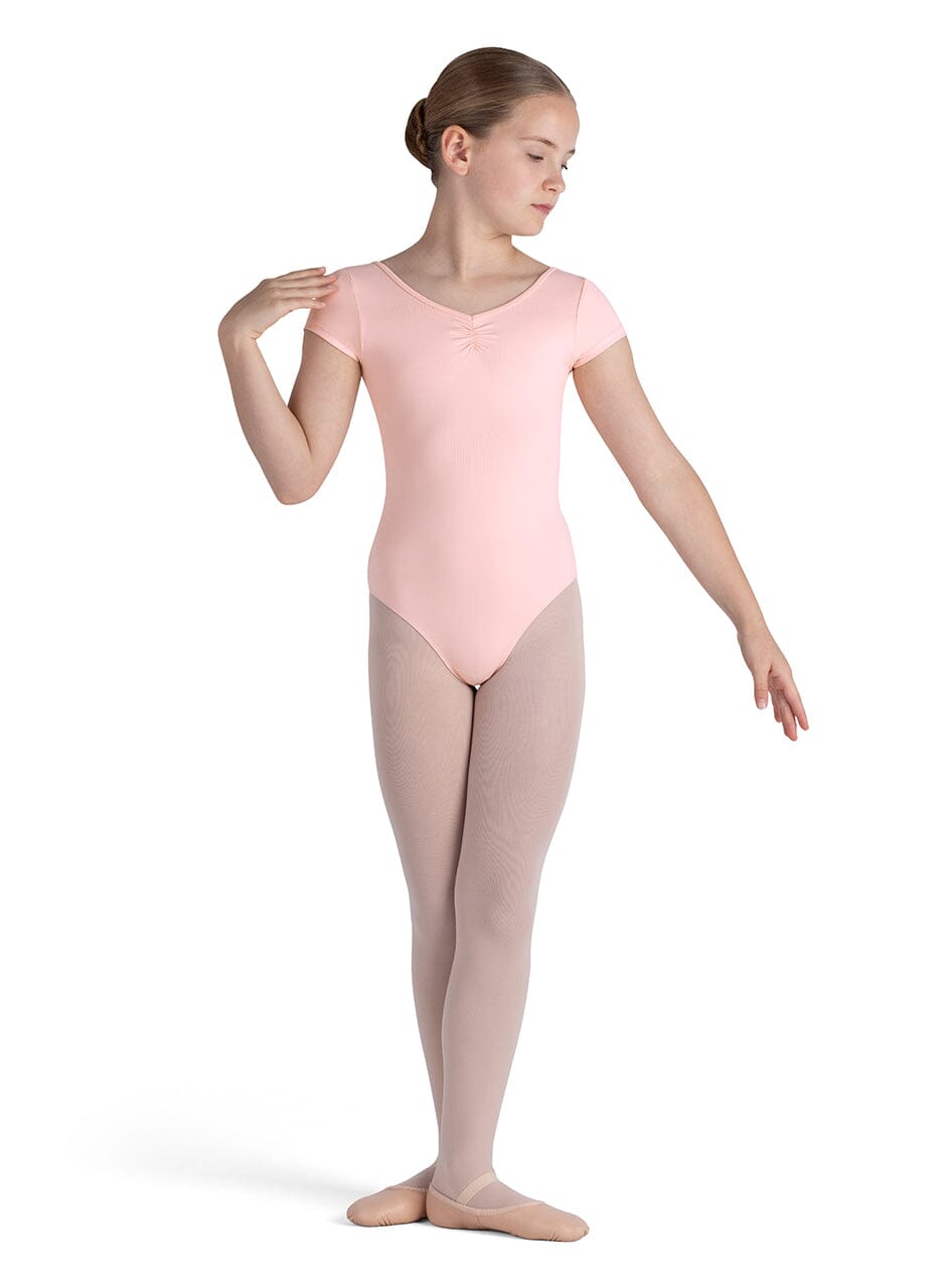 Young girl in a pink leotard and beige tights on a white background