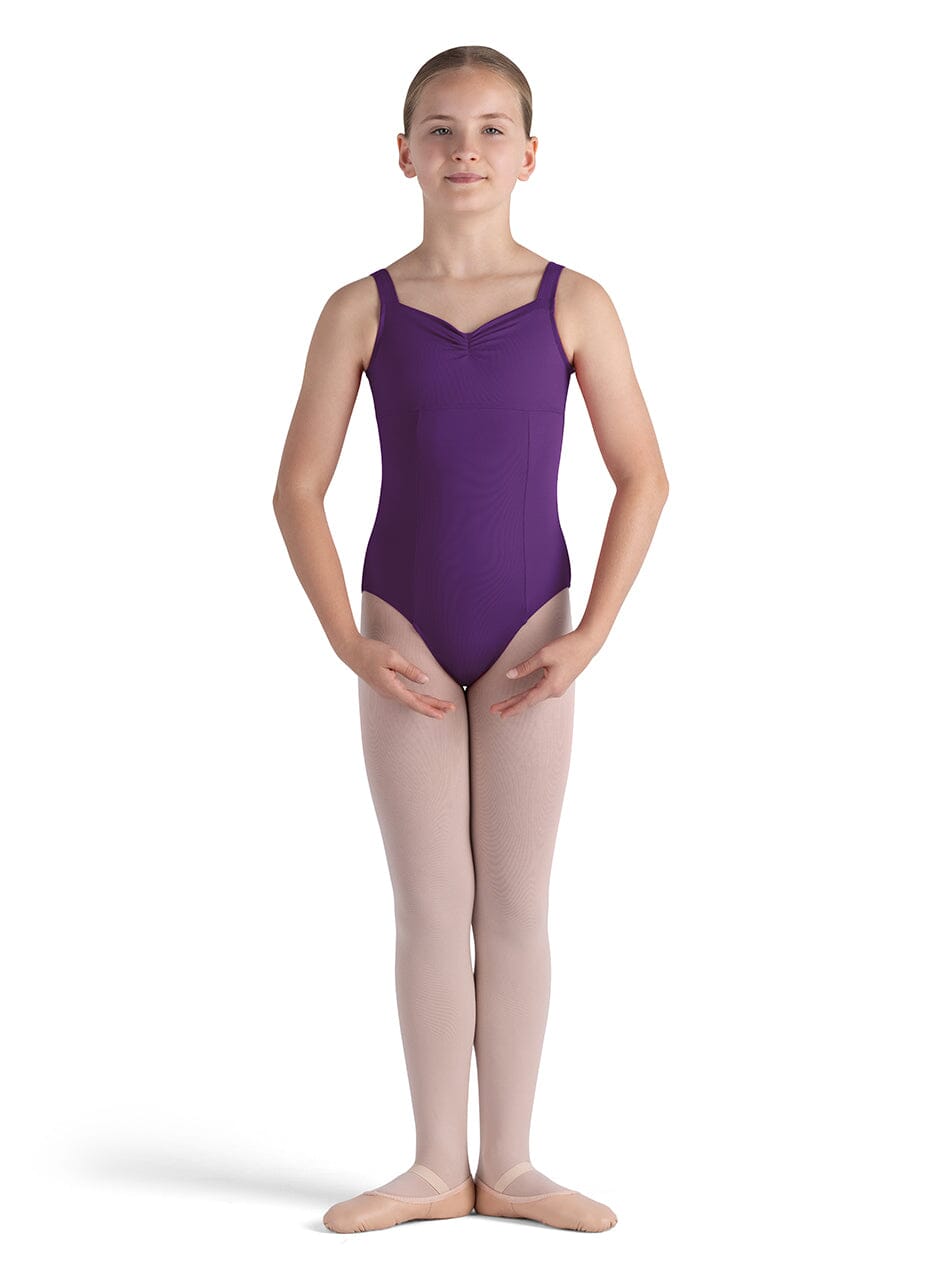 Young girl wearing a purple leotard and beige tights on a white background