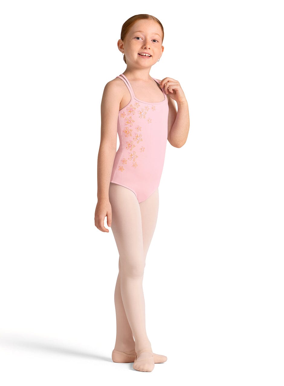 Young girl wearing a pink leotard with floral patterns on a white background