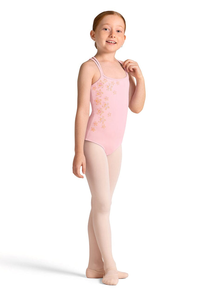 Young girl wearing a pink leotard with floral patterns on a white background
