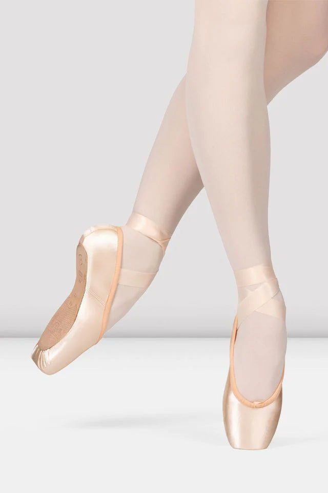 Ballet shoes worn with tights on a plain background