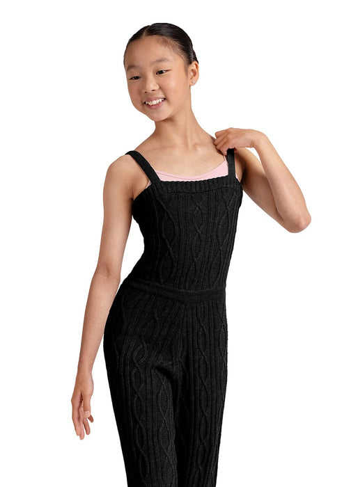 Young girl wearing a black cable knit jumpsuit on a white background
