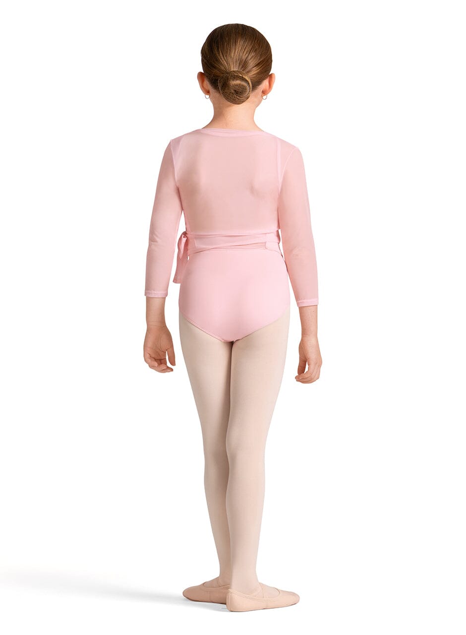 Young girl in a pink ballet outfit standing on a white background